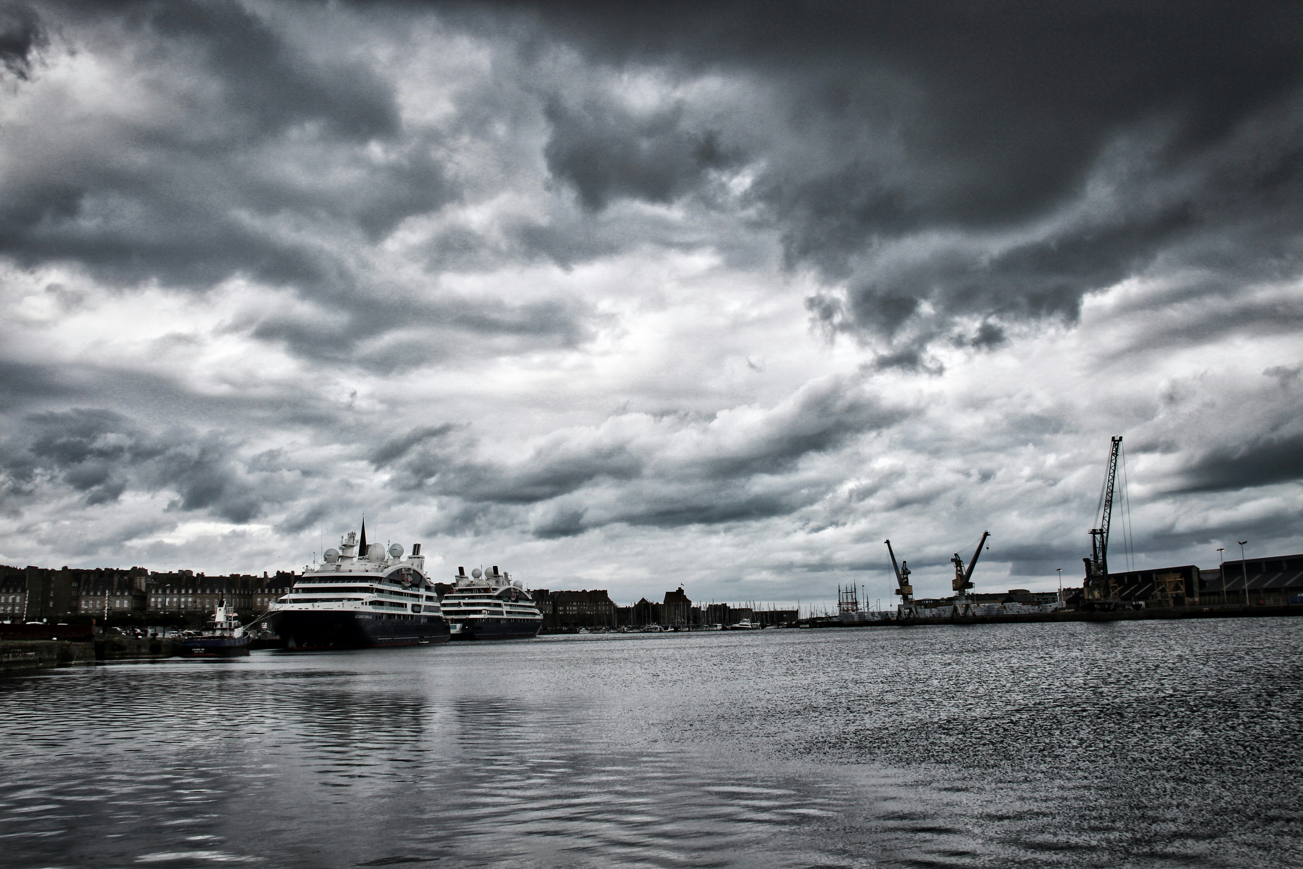 Cruise vessels and shipyard cranes under storm clouds