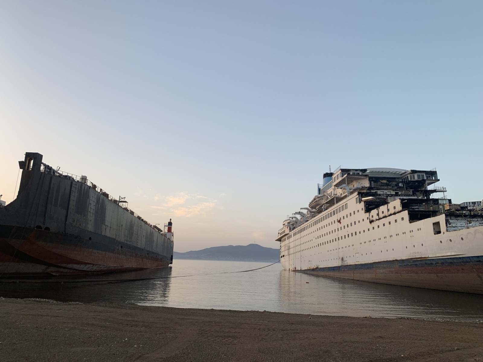 Two vessels at recycling yard during dismantling at dusk